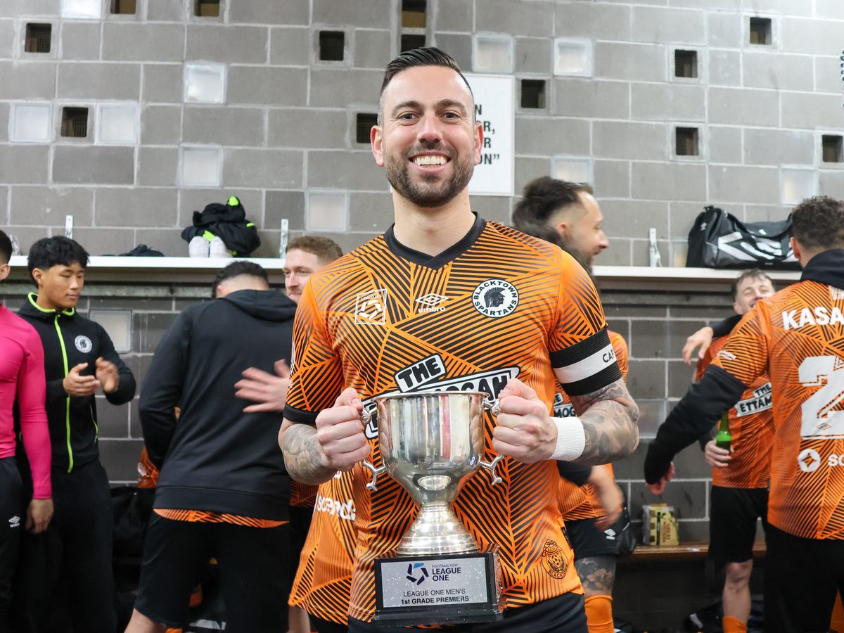 Spartans captain holding the League One Men's 1st Grade Premiers trophy in the change room
