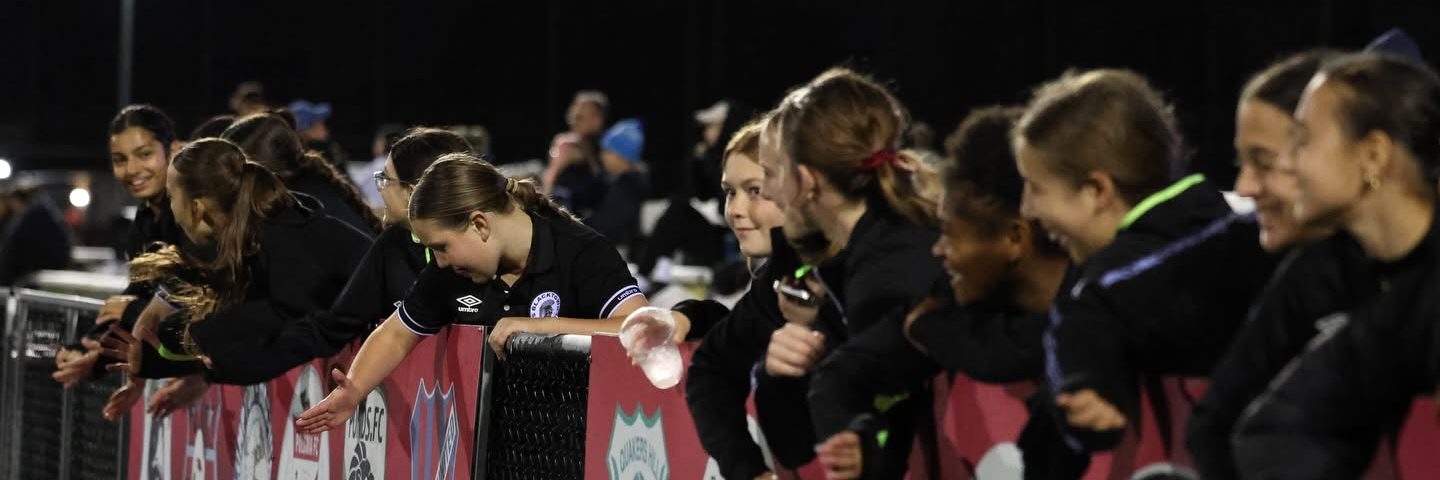 Young players high-fiving the team over the fence on match night